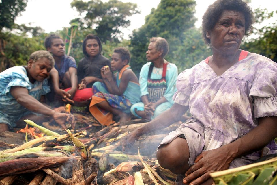 Ruth Nafow (R) cooks corn to sell at a local farmer's market on December 06, 2019 in Tanna, Vanuatu. Asked about climate change, she said, 'It's a really big concern. This will affect our crops in one way or another.'