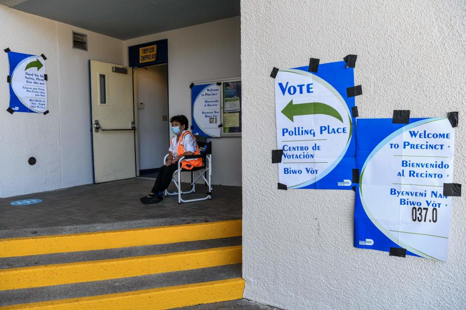 A poll worker sits outside a poling center in Miami Beach, Florida on August 18, 2020.