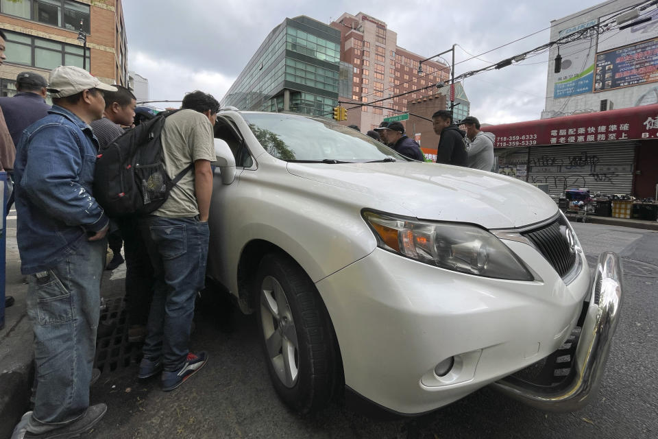 Wang Gang, 36, center left, a Chinese immigrant, talks with the driver of a car with others as they try to get a daily paid job working construction or in another trade in the Flushing neighborhood of the Queens borough of New York on May 3, 2024. The daily struggle to find work for Chinese immigrants living illegally in Flushing is a far cry from the picture Donald Trump and other Republicans have sought to paint about them. Asian advocacy organizations say they're concerned the exaggerated rhetoric could fuel further harassment against Asians in the U.S. (AP Photo/Fu Ting)