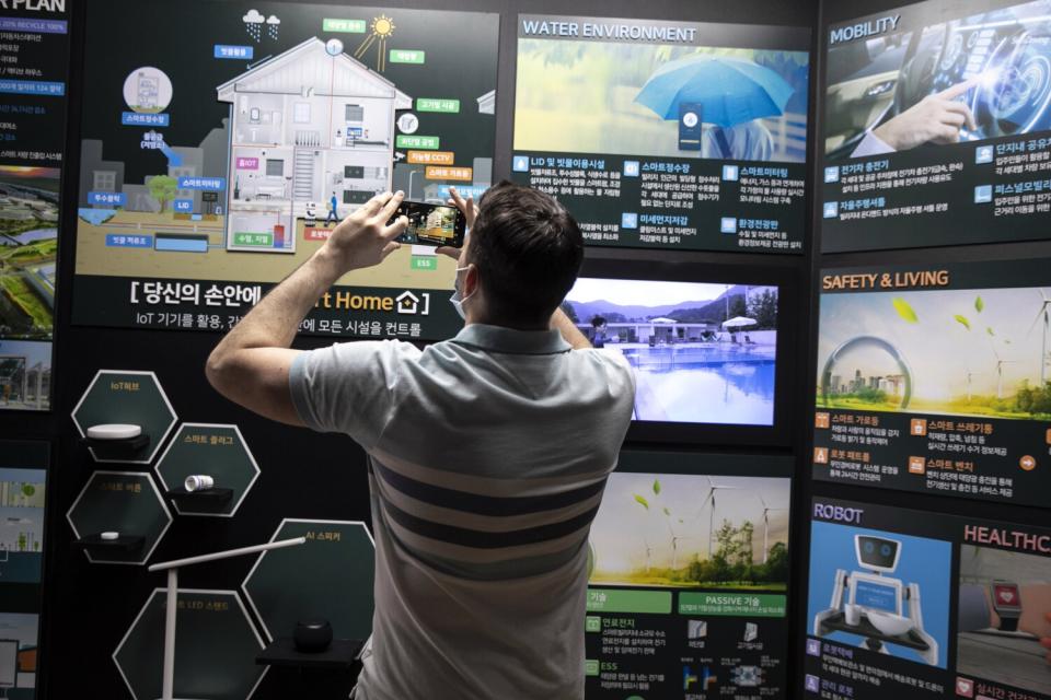 A man takes photos of panels illustrating a "smart home"