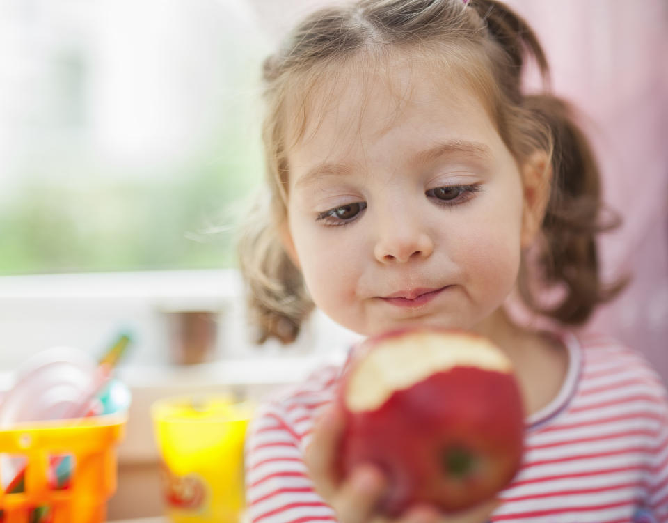 Closeup photograph of  little cute girl eating apple