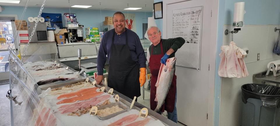 Blue Ocean Fish Market owner Luis Delgado holds up a fresh fish for sale at his store on Feb. 8, 2024. He works along side his brother-in-law Gregory Clark to clean, cut and filet fish for his customers.