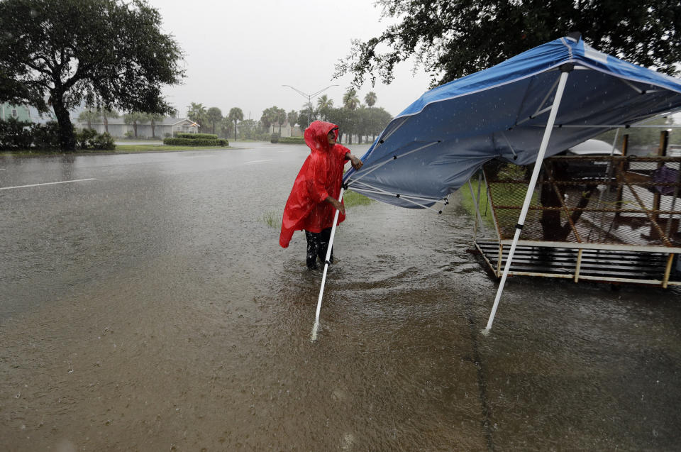 Jesus Escavado takes down a tent as heavy rains from Tropical Depression Imelda flood the streets in Galveston, Texas, Wednesday, Sept. 18, 2019. (AP Photo/David J. Phillip)