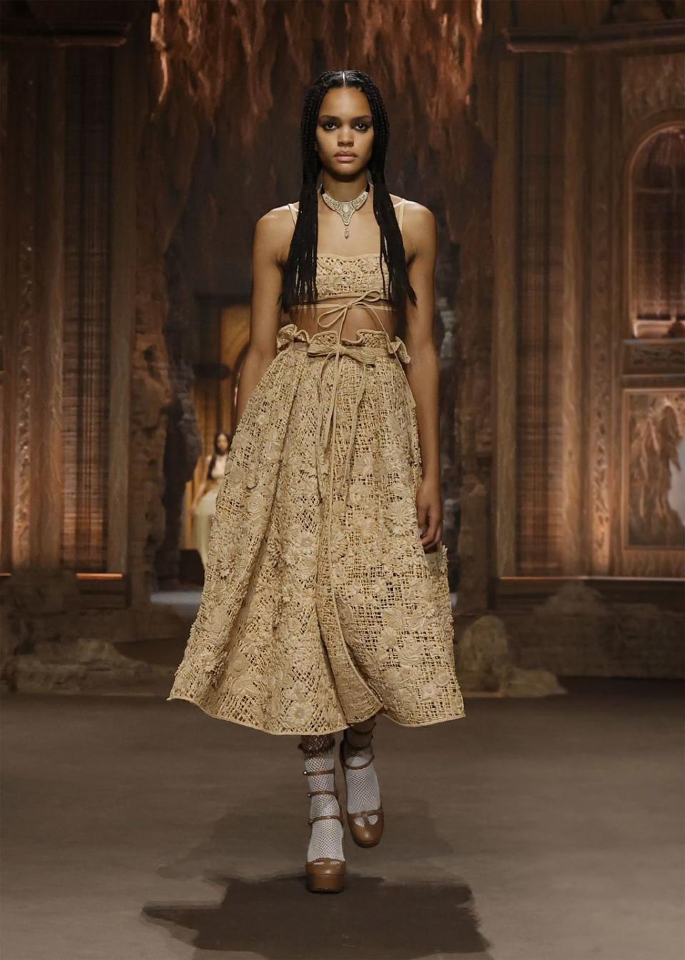 model walking the runway in a rattan dress and long braids