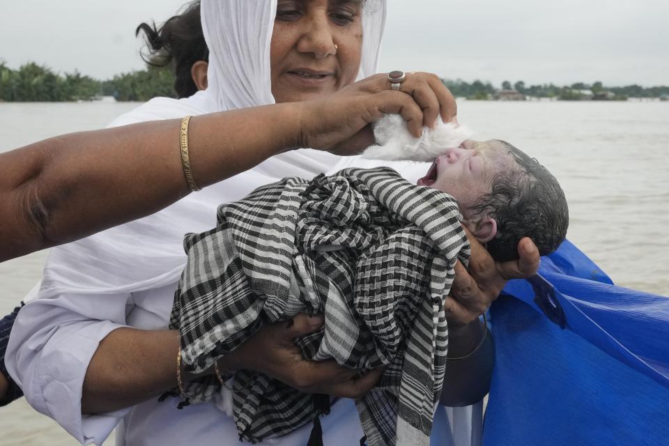 Midwife Diluwara Begum holds a newborn baby girl after helping in her delivery on a boat over the River Brahmaputra, in the northeastern Indian state of Assam, July 3, 2024. (AP Photo/Anupam Nath)