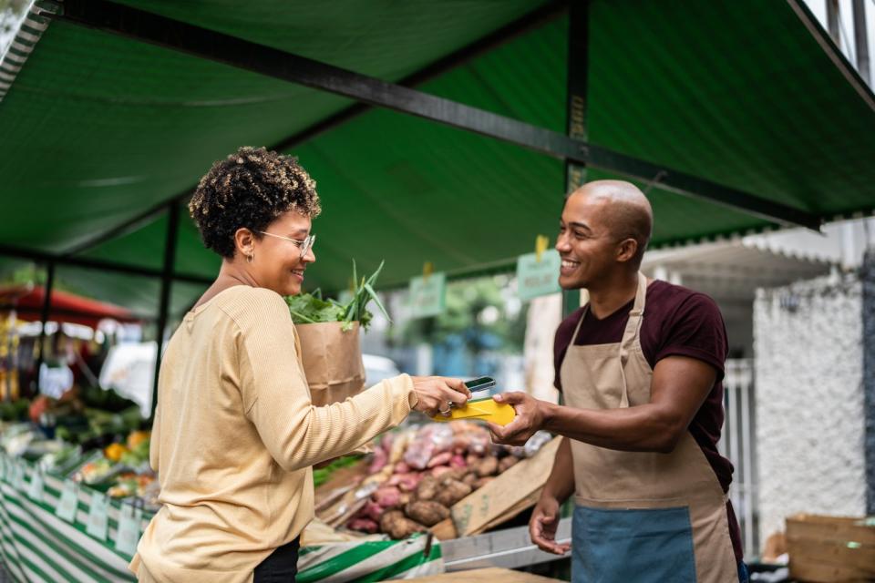 A person makes a digital payment in an outdoor market.