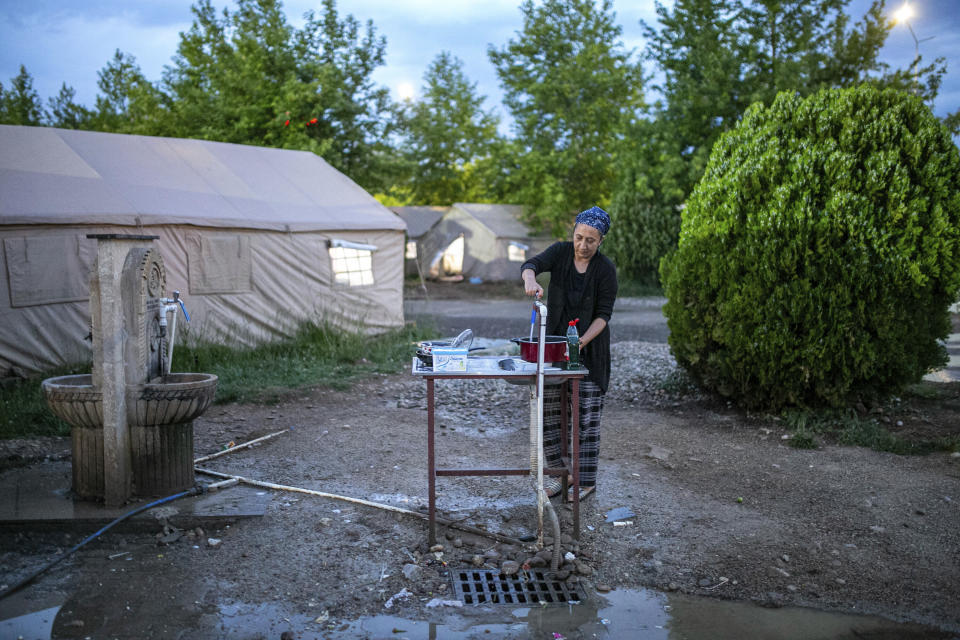 Songul Altintas collects water from a fountain next to tents where she and her family temporarily live after a powerful quake in Kahramanmaras, southeastern Turkey, Monday, May 22, 2023. Two opposing visions for Turkey’s future are on the ballot when voters return to the polls Sunday for a runoff presidential election, which will decide between an increasingly authoritarian incumbent President Recep Tayyip Erdogan and challenger Kemal Kilicdaroglu, who has pledged to restore democracy. (AP Photo/Metin Yoksu)