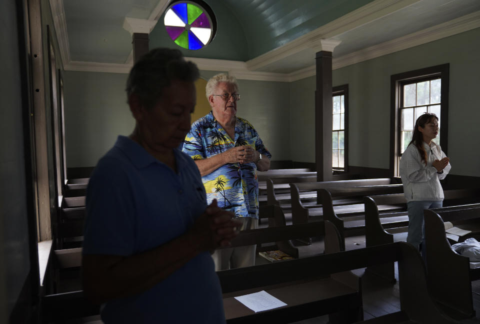 Sister Alicia Damien Lau, left, the Rev. Patrick Killilea, center, and Yunra Huh, pray together in the original chapel of St. Philomena Church during an impromptu Mass on Tuesday, July 18, 2023, in Kalaupapa, Hawaii. The church was expanded and used by Saint Damien and his parishioners in the 1800s while he lived with and cared for leprosy patients banished to Kalaupapa. (AP Photo/Jessie Wardarski)