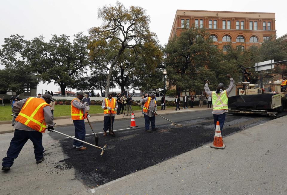 Workers repave the spot where U.S. President John F. Kennedy was hit by the first bullet in 1963 the day before 50th anniversary commemorations of the assassination in Dallas