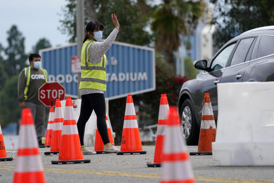 Cars are waved in as people arrive at the Dodger Stadium parking lot to receive the COVID-19 vaccine Monday, Feb. 1, 2021, in Los Angeles. One of the largest vaccination sites in the nation temporarily shut down Saturday because dozen of protesters blocked the entrance, stalling hundreds of motorists who had been waiting in line for hours. Officials say the Los Angeles Fire Department shut the entrance to the vaccination center at Dodger Stadium. (AP Photo/Mark J. Terrill)