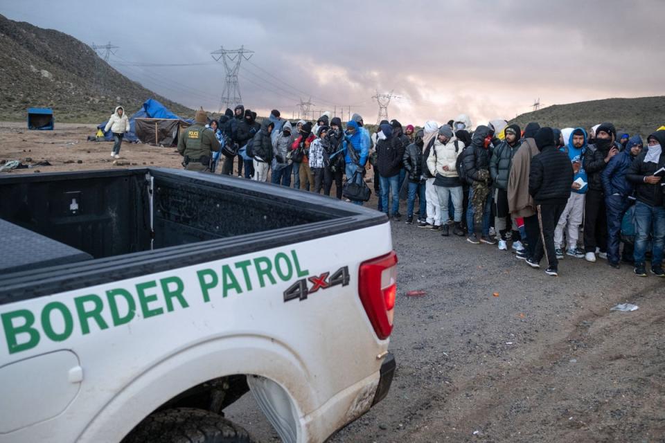 People seeking asylum wait in line to be processed by border patrol agents near the US-Mexico border outside California on 2 January (AFP via Getty Images)