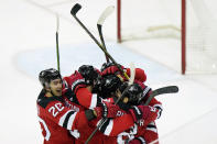 New Jersey Devils center Michael McLeod (20) surrounds teammates, including New Jersey Devils center Pavel Zacha (37), center, (seen only by his helmet) after Zacha scored a game-winning goal in playoff-bound Boston Bruins, Tuesday, May 4, 2021, in Newark, N.J. (AP Photo/Kathy Willens)