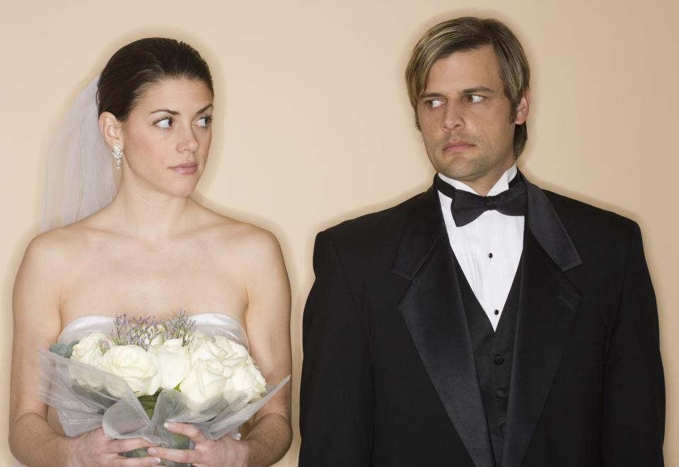 An unhappy bride and groom stand next to each other