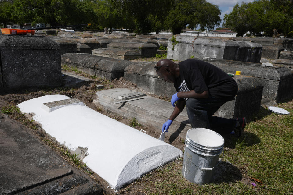 Frank Wooden paints a grave at the Lincoln Memorial Park Cemetery, Monday, Feb. 26, 2024, in the Brownsville neighborhood of Miami. Wooden became the caretaker after his brother, Jessie, purchased the historically segregated Black cemetery where their mother was buried. They have cleaned, painted and maintained the cemetery and they are still burying residents. (AP Photo/Marta Lavandier)