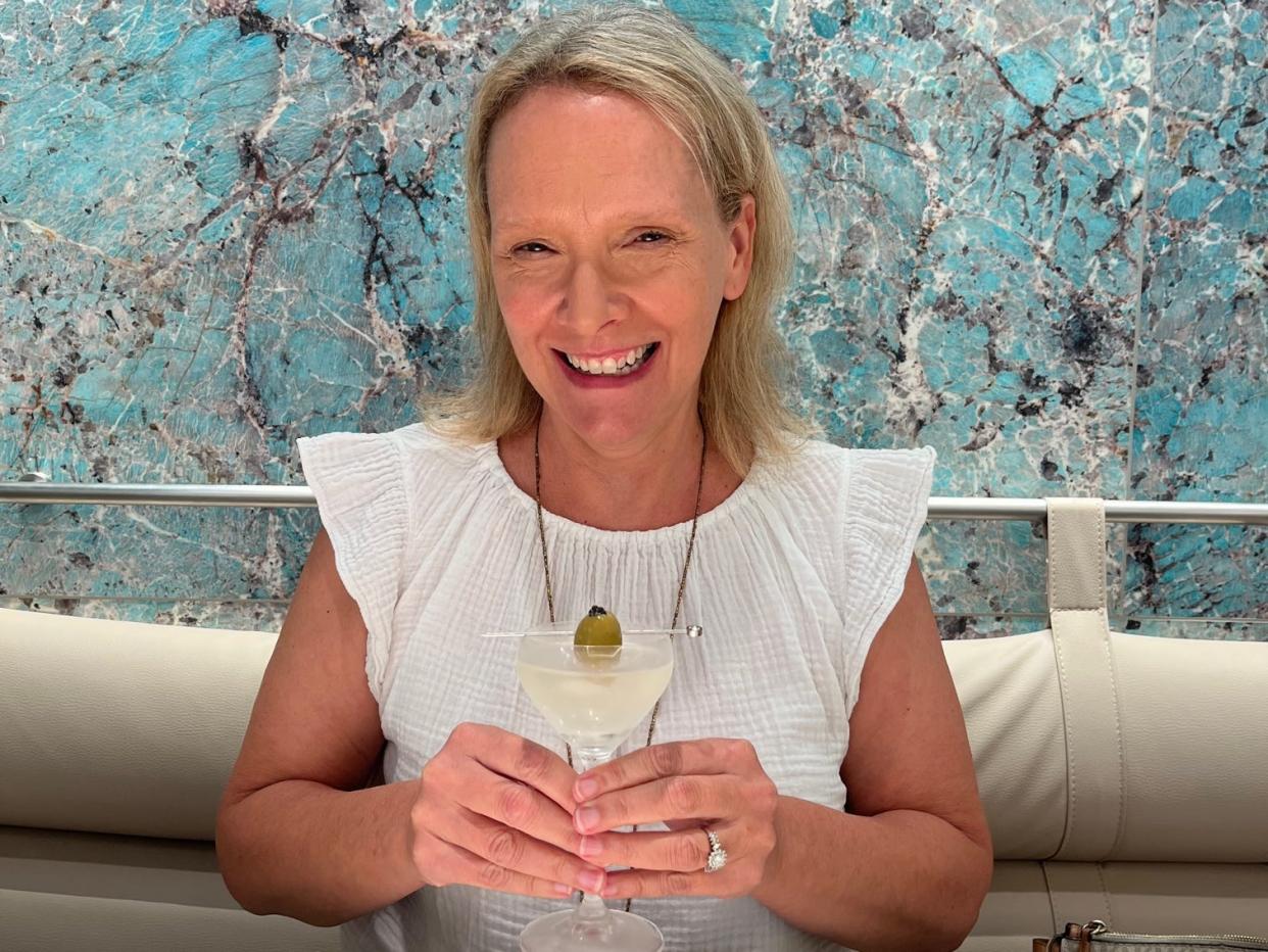 Petrossian Wendy Lee with Tiffany Caviartini, smiling with glass in hand and blue wallpaper in background