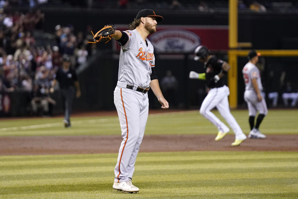 Baltimore Orioles starting pitcher Cole Irvin gets a new baseball after giving up a two-run home run to Arizona Diamondbacks' Lourdes Gurriel Jr. as Diamondbacks' Ketel Marte, second from right, rounds the bases past Orioles third baseman Ramon Urias during the first inning of a baseball game Friday, Sept. 1, 2023, in Phoenix. (AP Photo/Ross D. Franklin)