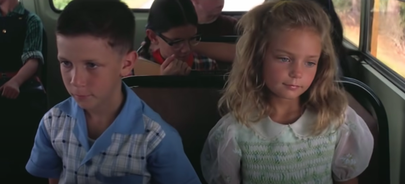 A young boy and girl sit together on the bus