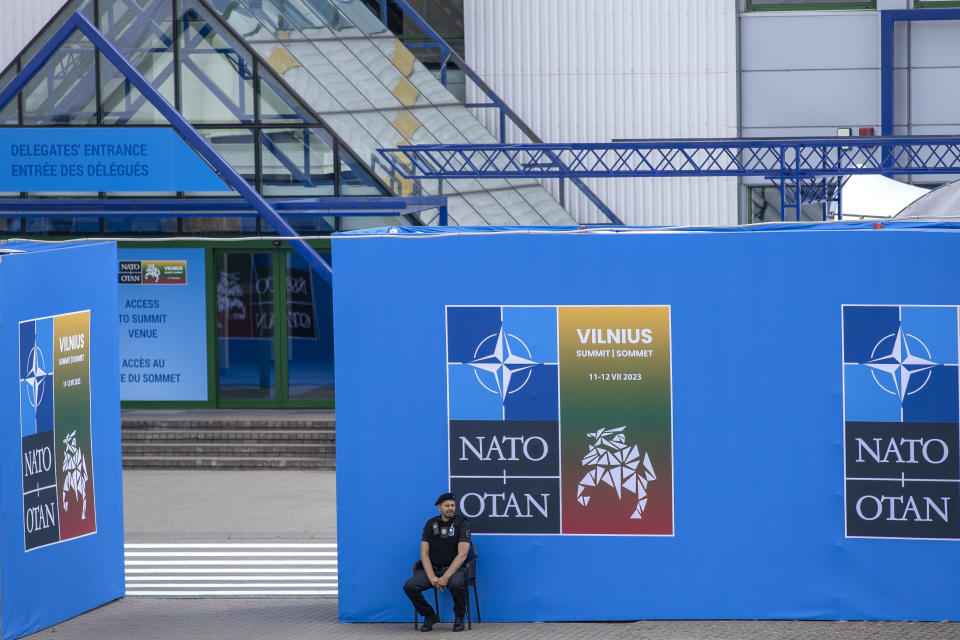 A security guard sits in front of a banner outside the venue of the NATO summit in Vilnius, Lithuania, Sunday, July 9, 2023. Russia's war on Ukraine will top the agenda when U.S. President Joe Biden and his NATO counterparts meet in the Lithuanian capital Vilnius on Tuesday and Wednesday. / Credit: Mindaugas Kulbis / AP