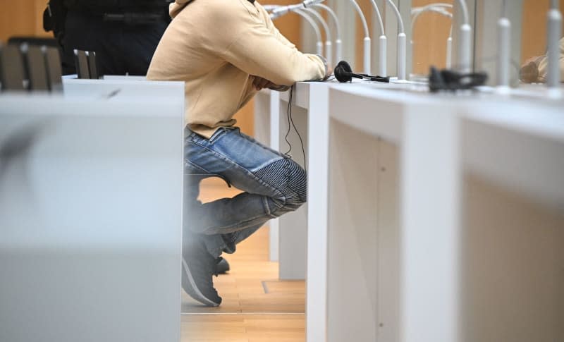 A defendant from Eritrea sits in a courtroom before the start of his trial. A 29-year-old Eritrean man has been charged with a severe breach of the peace, serious bodily harm, and reportedly attacking police officers. Bernd Weißbrod/dpa