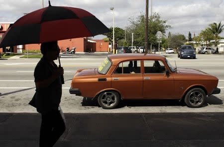 A woman walks past a Moskvich car in front of Fabian Zakharov's Zakharov Auto Parts shop in Hialeah, Florida, February 4, 2015. REUTERS/Javier Galeano