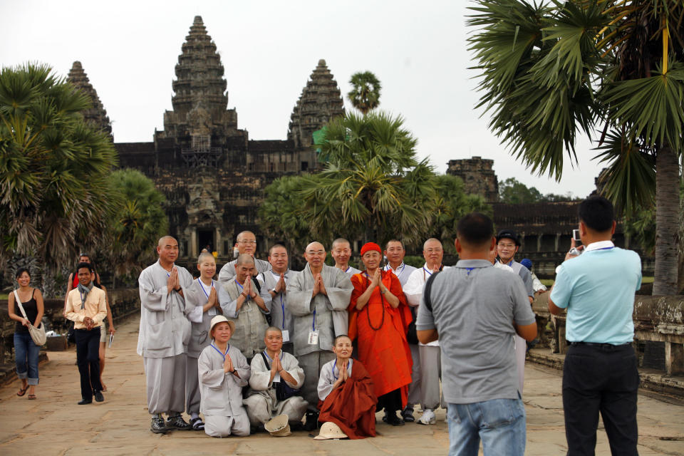 SIEM REAP, CAMBODIA - NOVEMBER 20: Korean tourists get their photo taken on the grounds of the Angkor Wat temple November 20, 2007 in Siem Reap, Cambodia. Tourism continues to grow to an average of 30 percent a year with new shopping centers and hotels lining the streets of Siem Reap. The Angkor Wat temple is a fast growing tourist destination with 1.7 million visiting last year. Preservationists in Cambodia, one of Southeast Asia's poorest countries, are seriously concern over damages created by constant overcrowding in touring the temple with numbers exceeding the capacity the site can manage. Angkor Wat was built between the ninth and fifteenth centuries, but was officially rediscovered in 1860 by French naturalist Henri Mouhot. The temple was later restored with the help of both UNESCO and archaeologists from France and Japan. (Photo Paula Bronstein/Getty Images)