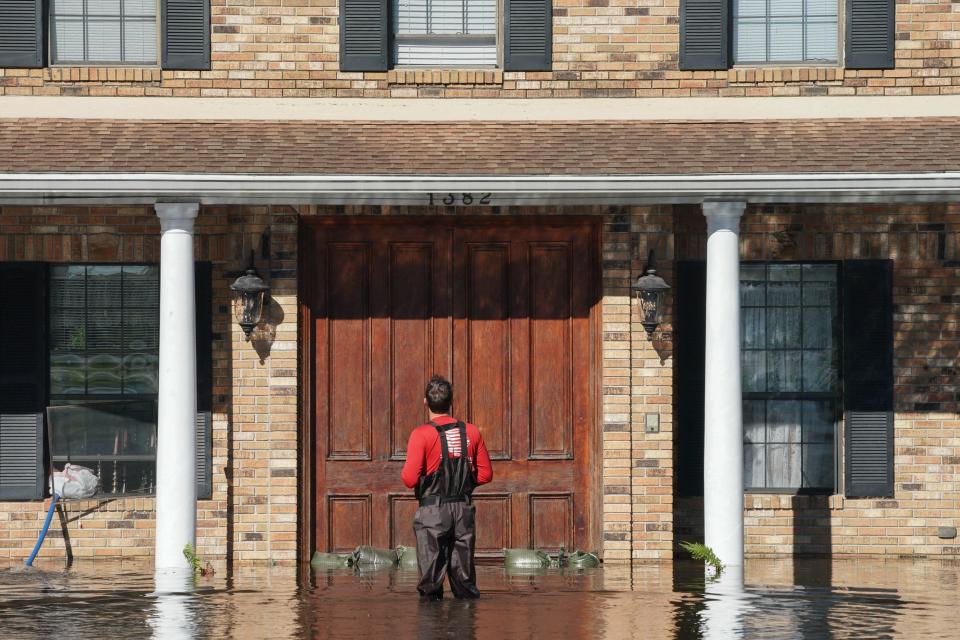 A man stops in front of his house as a creek overflows from flooding following Tropical Storm Ian on September 30, 2022 in Kissimmee, Florida.  / Credit: BRYAN R. SMITH/AFP via Getty Images