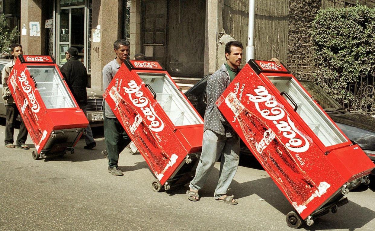 Egyptian workers push Coca-Cola branded refrigerators, provided free to grocers, through a Cairo street. <a href="https://www.gettyimages.com/detail/news-photo/egyptian-workers-push-coca-cola-refrigerators-through-a-news-photo/140974398" rel="nofollow noopener" target="_blank" data-ylk="slk:Mohammed Al-Sehiti/AFP via Getty Images;elm:context_link;itc:0;sec:content-canvas" class="link ">Mohammed Al-Sehiti/AFP via Getty Images</a>