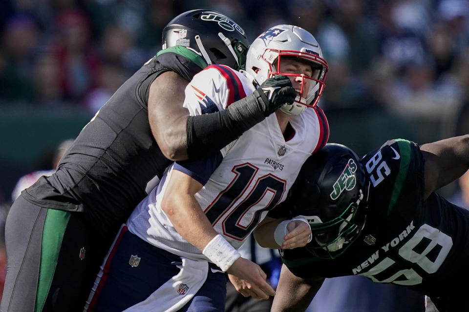 New York Jets defensive end John Franklin-Myers, left, and defensive end Carl Lawson (58) put a late hit on New England Patriots quarterback Mac Jones (10) during the second quarter of an NFL football game, Sunday, Oct. 30, 2022, in New York. (AP Photo/John Minchillo)