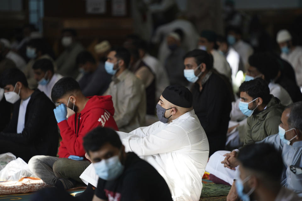 Men wearing face masks sit inside Manchester Central Mosque, in Manchester, northern England, after having their temperatures checked at the entrance to try stop the spread of coronavirus, as Muslims worldwide mark the start of the Eid al-Adha holiday, Friday, July 31, 2020. The British government on Thursday night announced new rules on gatherings in some parts of Northern England, including Manchester, that people there should not mix with other households in private homes or gardens in response to an increase trend in the number of cases of coronavirus cases per 100,000 people. (AP Photo/Jon Super)