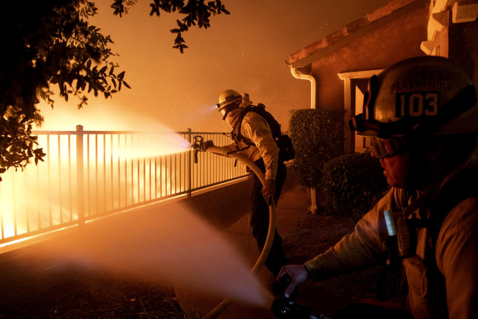 In this Thursday, Oct. 10, 2019 photo, Los Angeles City firefighters battle the Saddleridge fire near homes in Sylmar, Calif. (AP Photo/Michael Owen Baker)
