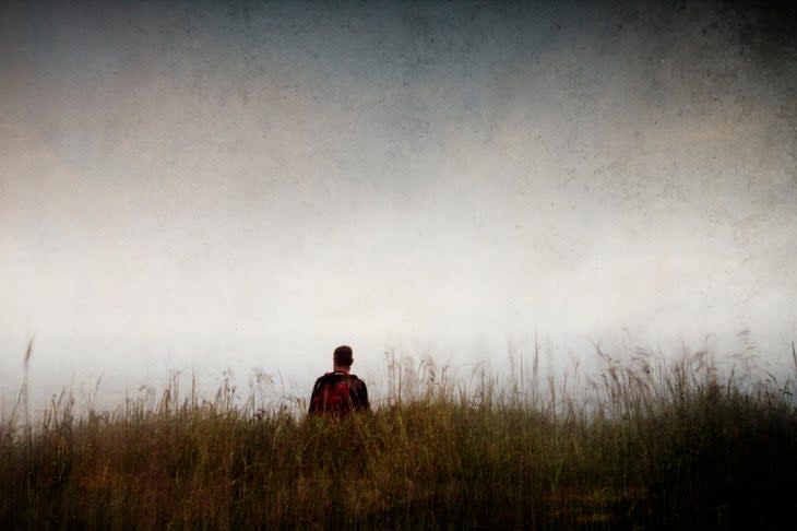 A hiker alone, standing in a field. With a grunge, artistic edit