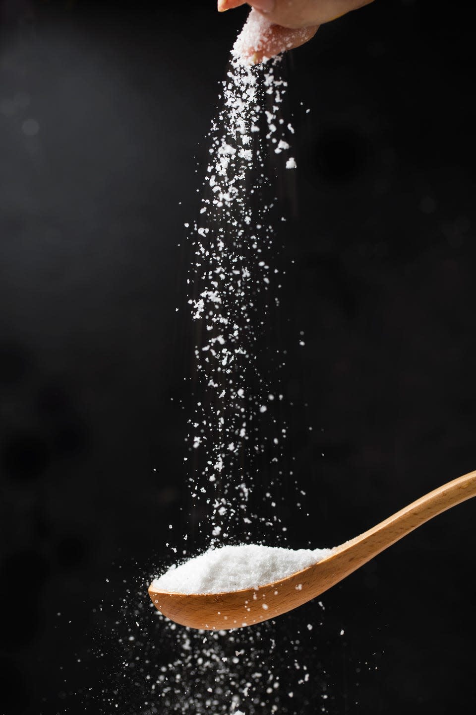 salt in wooden spoon on black background