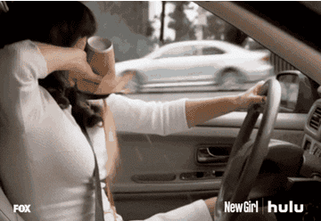 woman spilling coffee on herself while driving