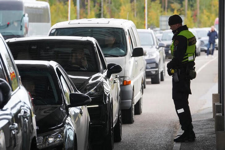 Un agente de la guardia fronteriza finlandesa junto a los automóviles que hacen cola para entrar en Finlandia desde Rusia en Vaalimaa, Finlandia