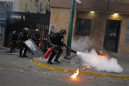 A national policeman extinguishes a petrol bomb, thrown at them by anti-government protesters, during a protest at Altamira square in Caracas March 13, 2014. REUTERS/Tomas Bravo