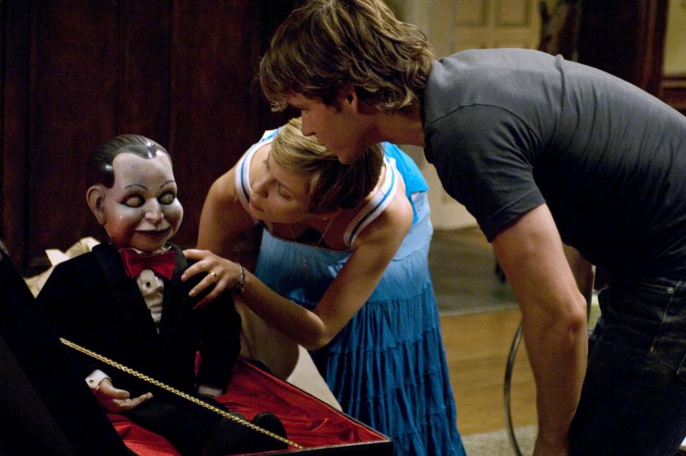 A young couple examines a dusty puppet in a fine box