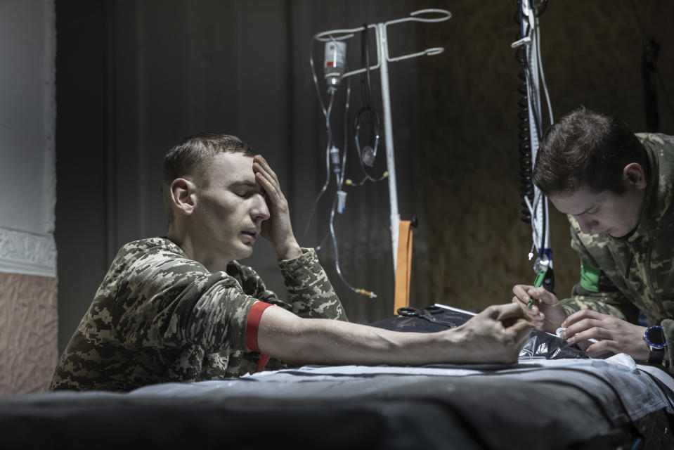 A medic gives the first aid to a wounded Ukrainian soldier near Bakhmut, the site of the heaviest battles with the Russian troops, Donetsk region, Ukraine, Monday, Feb. 27, 2023. (AP Photo/Yevhen Titov)