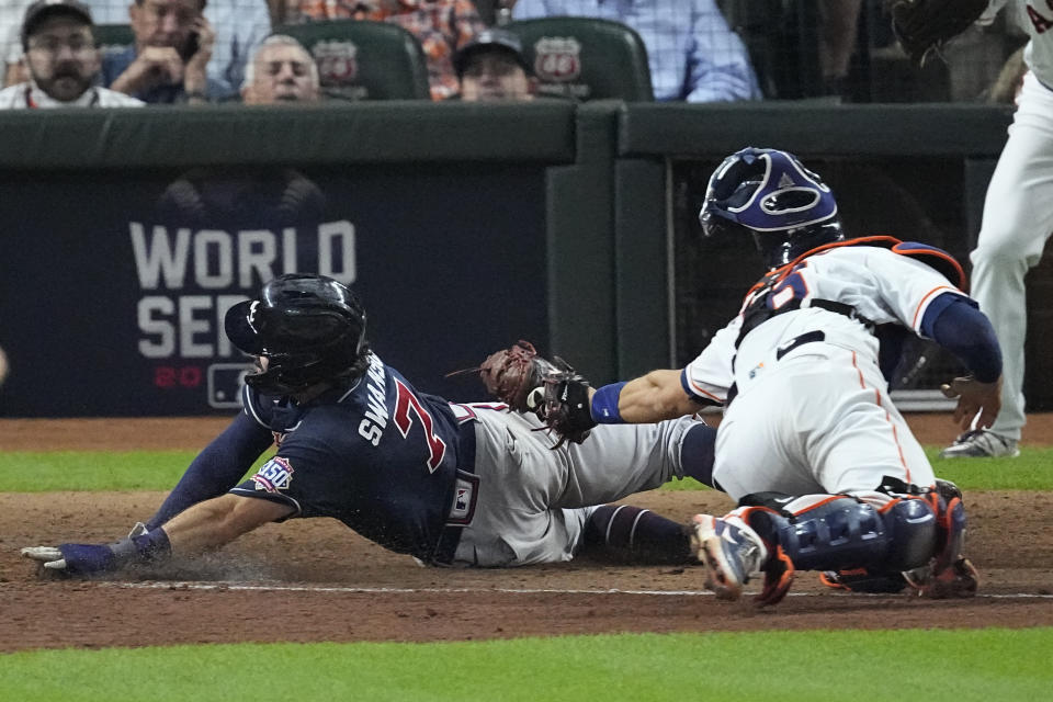 Atlanta Braves' Dansby Swanson scores past Houston Astros catcher Jason Castro on a sacrifice fly during the eighth inning of Game 1 in baseball's World Series between the Houston Astros and the Atlanta Braves Tuesday, Oct. 26, 2021, in Houston. (AP Photo/Sue Ogrocki)