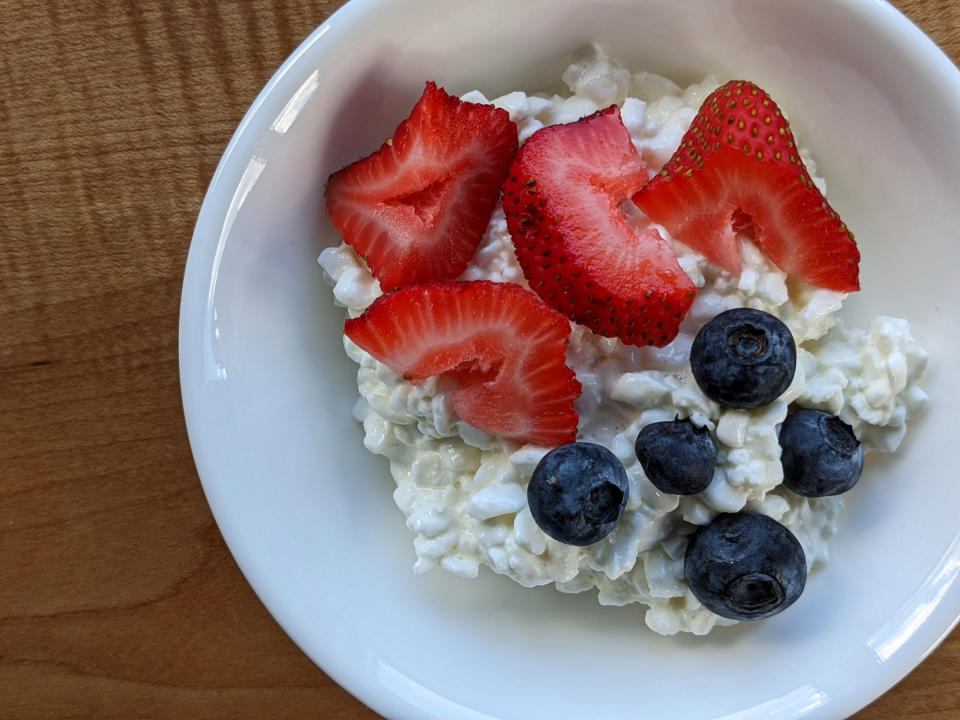 Red strawberries and blueberries on top of a bowl of cottage cheese