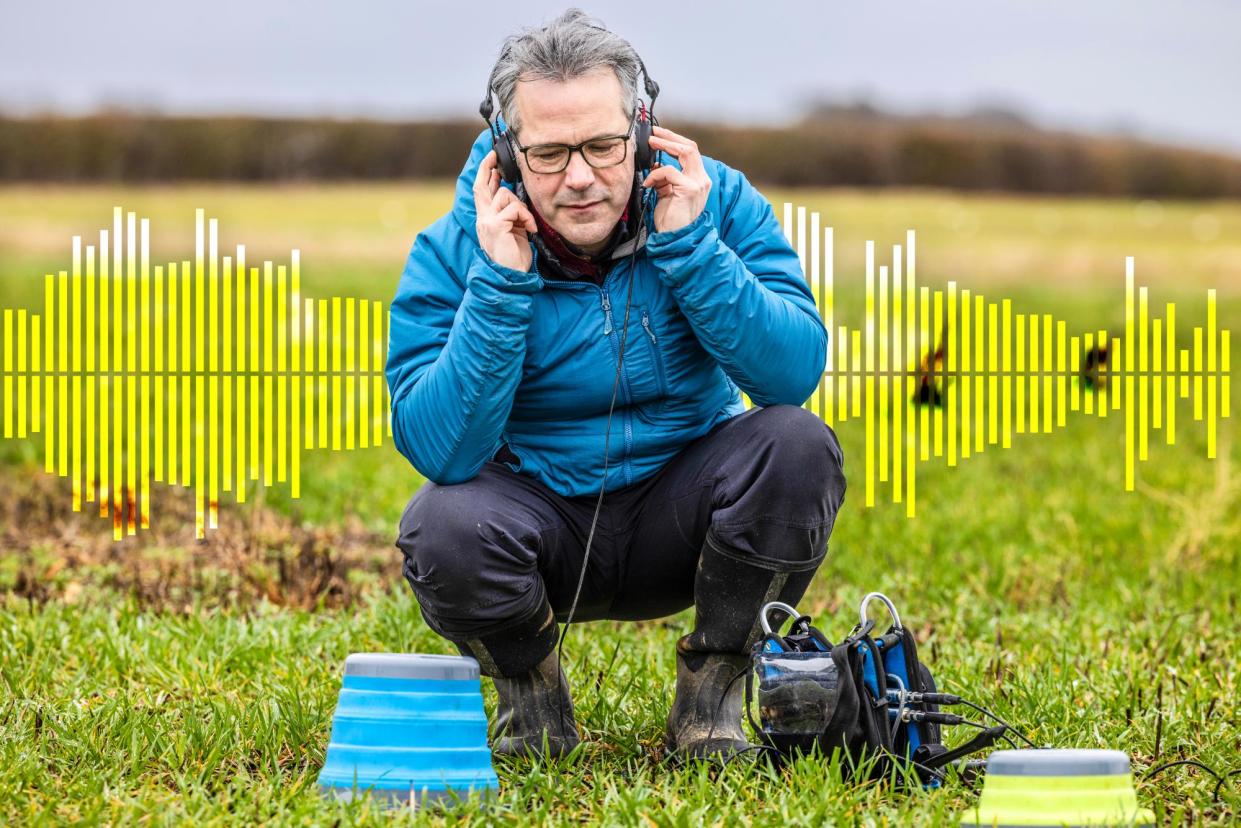 <span>Carlos Abrahams crouches on the grass in a field with headphones on.</span><span>Photograph: Graeme Robertson/The Guardian</span>