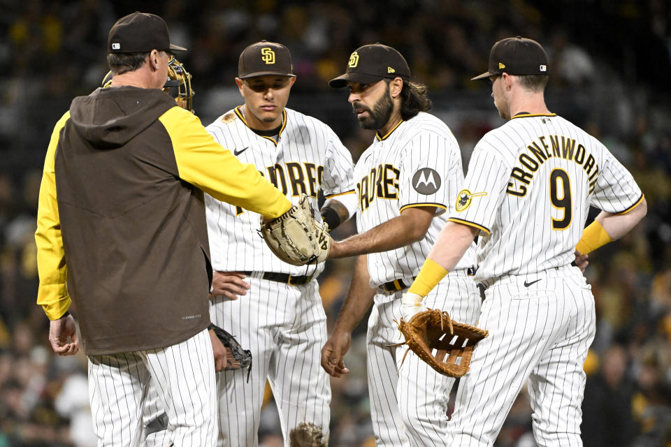 San Diego Padres manager Bob Melvin, left, hands the ball to relief pitcher Nabil Crismatt, second from right, during the fourth inning of a baseball game against the Colorado Rockies in San Diego, Thursday, March 30, 2023. (AP Photo/Alex Gallardo)