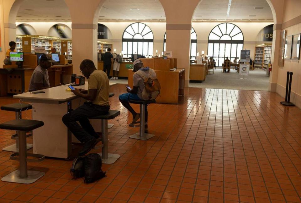 Varias personas cargan sus teléfonos en el aire acondicionado, el lunes 17 de julio de 2023, en una sucursal de la Biblioteca Pública de Miami-Dade, en el downtown de Miami.