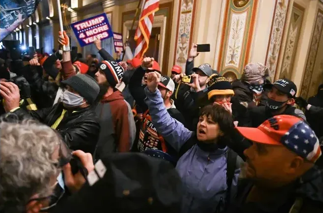 Sue Ianni photographed inside the U.S. Capitol during the Jan. 6 violent riot. Ianni is wearing  a blue jacket, with her fist extended.