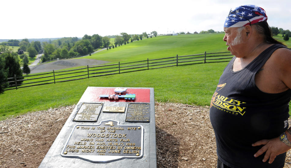 FILE - In this Aug. 14, 2009 file photo, Gypsy, who attended the 1969 Woodstock Festival looks at the memorial plaque at the site of the original Festival in Bethel, N.Y. A dispute over whether the Woodstock 50 festival will go on as planned in August 2019 has spiraled into a court fight, with organizers suing and at least temporarily silencing former investor London-based Dentsu Aegis Network, which stated that the event was cancelled, citing concern about artists' and attendees' "health and safety." (AP Photo/Stephen Chernin, File)