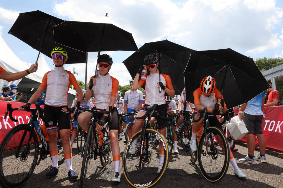 Annemiek van Vleuten, from left, Anna van der Breggen, Demi Vollering and Marianne Vos of the Netherlands protect from the sun with an umbrella before they compete in the women's cycling road race at the 2020 Summer Olympics, Sunday, July 25, 2021, in Oyama, Japan. (Michael Steele/Pool Photo via AP)