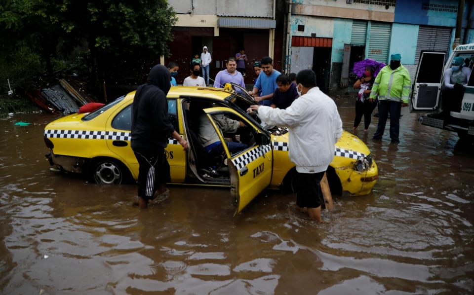 People try to move a taxi dragged by the water during floods caused by Tropical Storm Amanda at El Modelo neighborhood, in San Salvador (REUTERS)