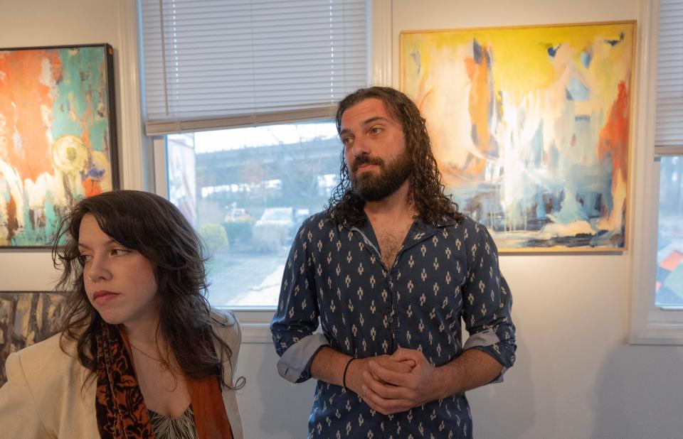 Brianna Montalto and Robert Testa stand before a display of artwork by deceased artist Lorraine Madsen, who continued painting while battling cancer in spite of nerve damage to her hands from the chemo treatment. The display is at the Belmar Arts Council.