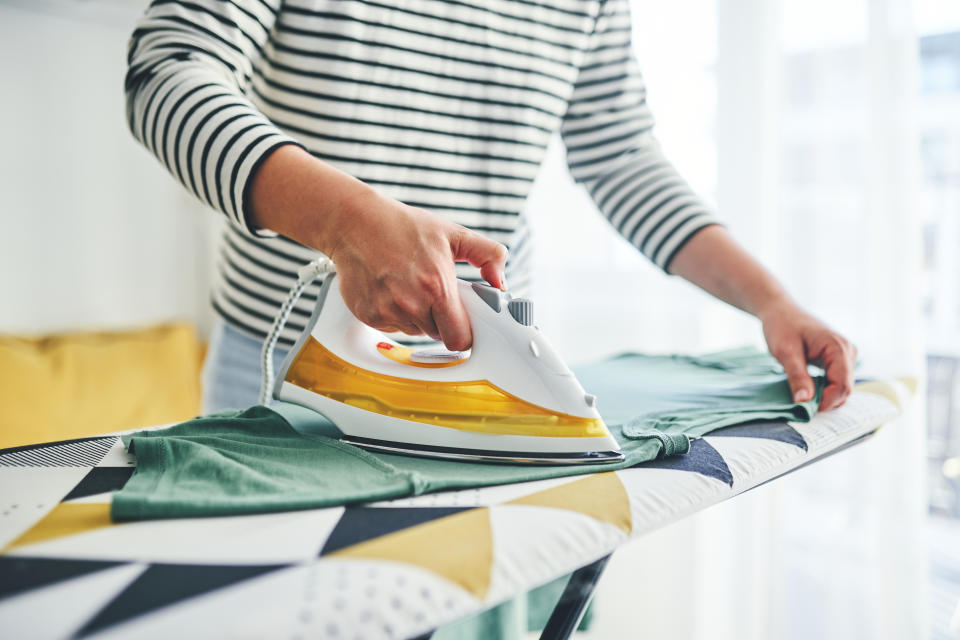 Someone ironing clothes on an ironing board