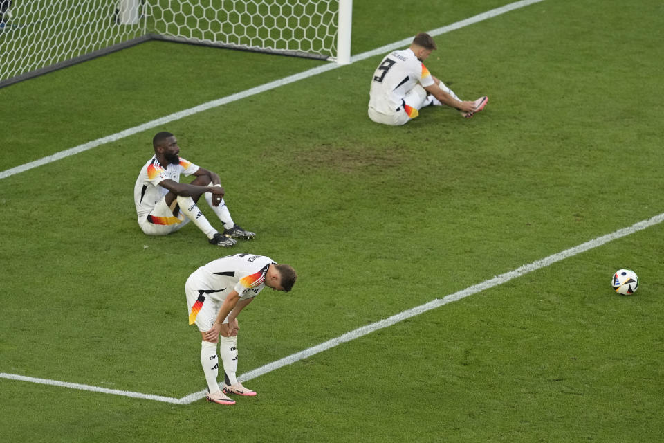 Germany's Joshua Kimmich, foreground reacts alongside Antonio Ruediger, top left and Niclas Fuellkrug at the end of a quarter final match between Germany and Spain at the Euro 2024 soccer tournament in Stuttgart, Germany, Friday, July 5, 2024. Spain won the game 2-1 after extra time. (AP Photo/Michael Probst)