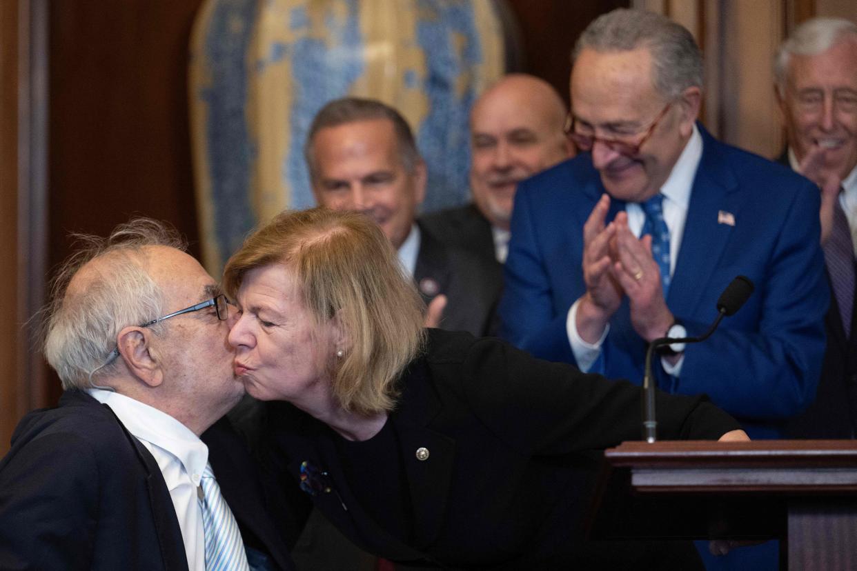 Former Congressman Barney Frank is kissed on the cheek by Senator Tammy Baldwin at the bill enrollment ceremony.